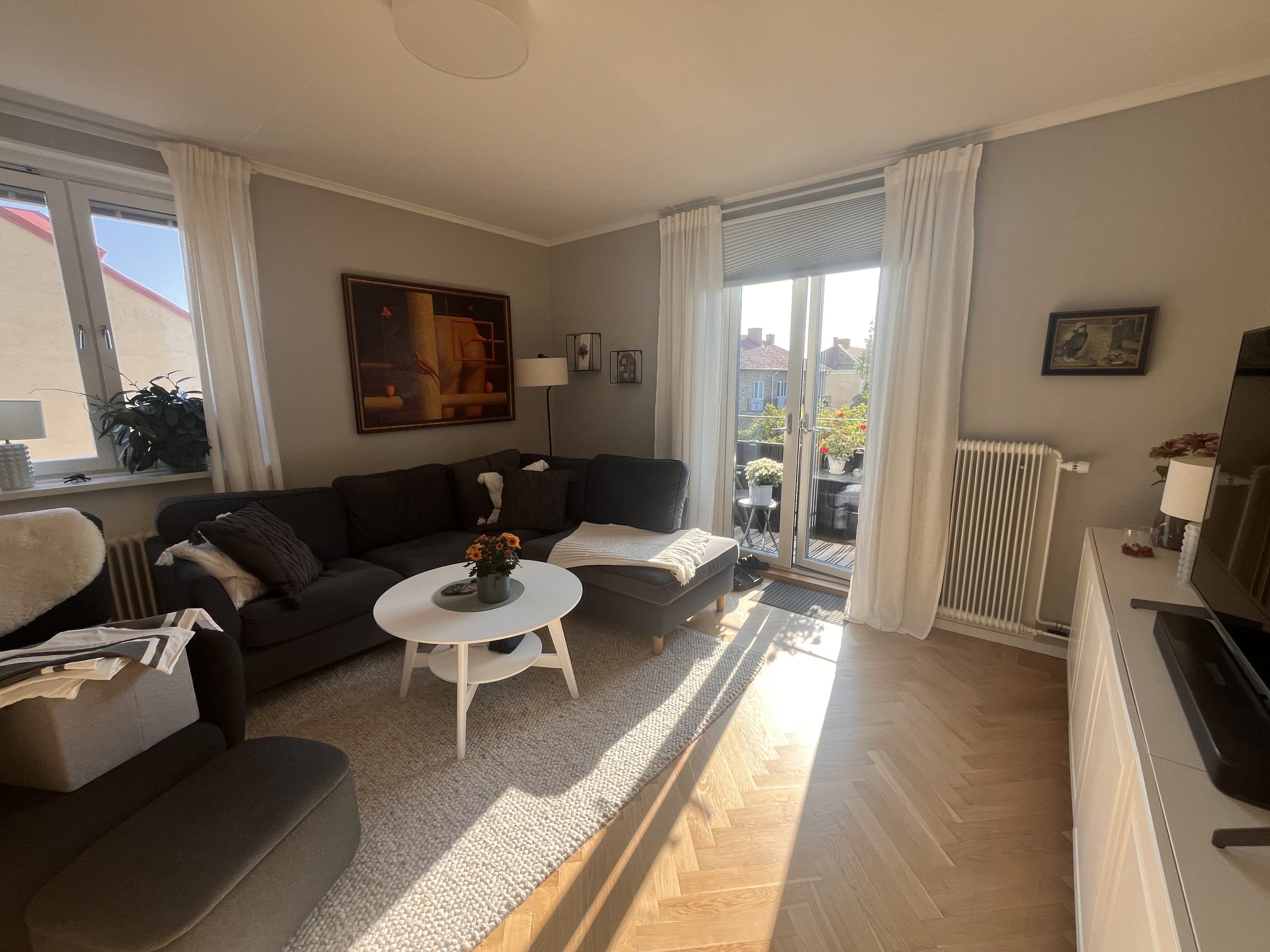 Vardagsrum med fiskbensparkett och balkongdörr på Lohegatan 16
